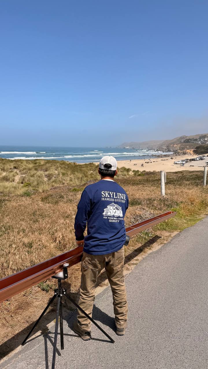 Skyline crew member carrying copper gutter Dillon Beach California coast