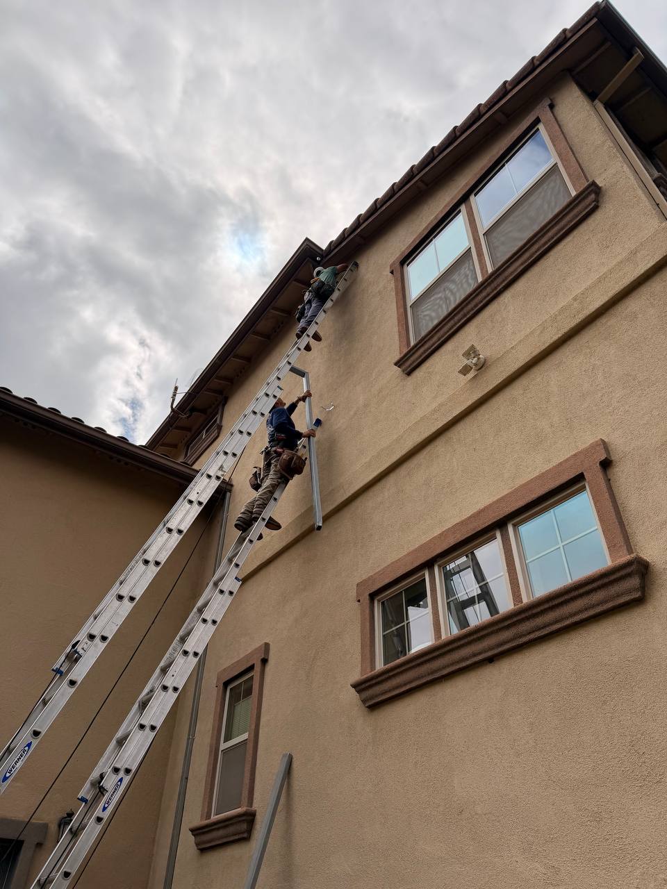 Close-up detail downspout secured to stucco wall bracket install