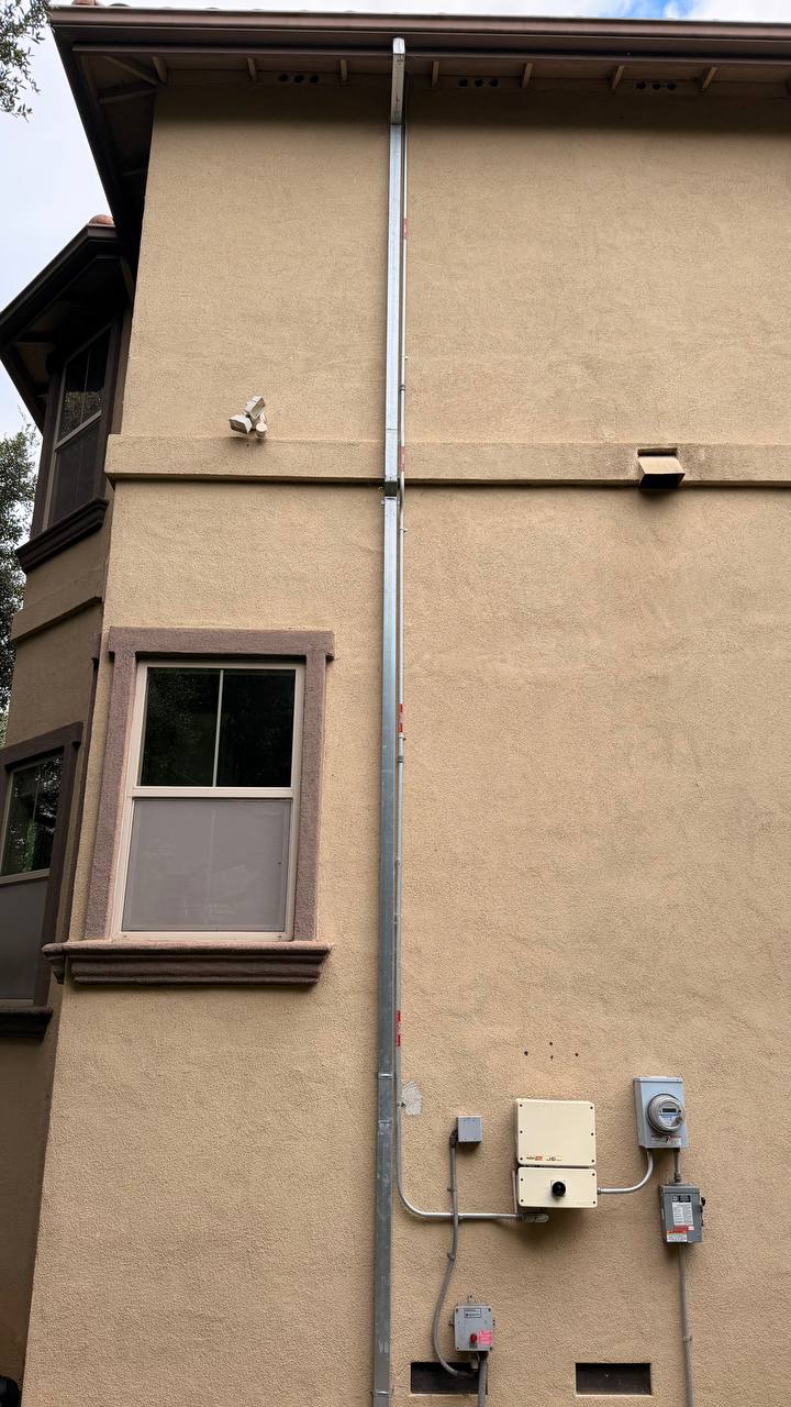 Full-height galvanized downspout run stucco three-story home clean routing