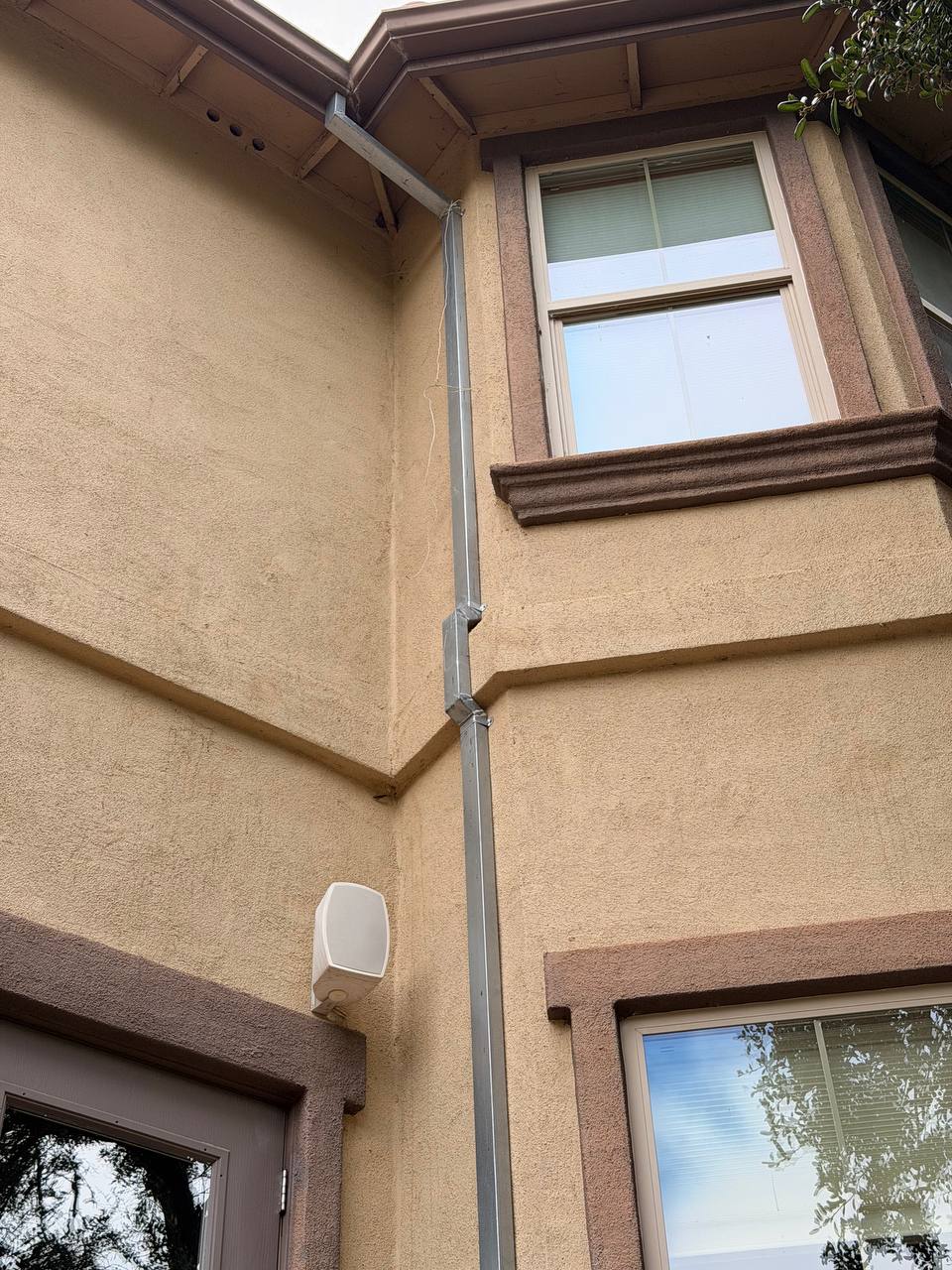 Two-person Skyline crew installing gutter on tall stucco home