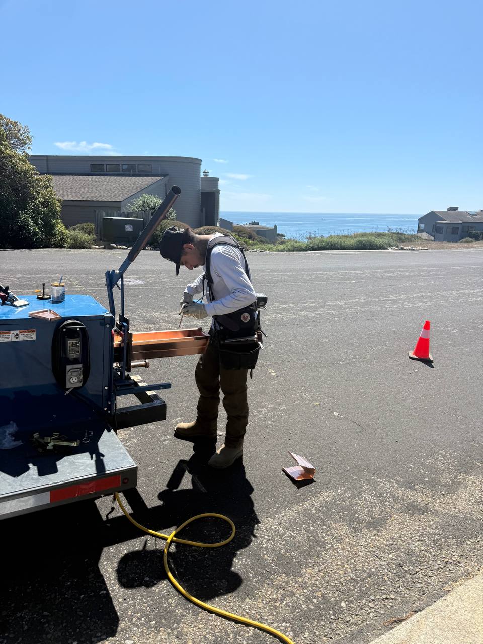 Copper gutter fabrication beside a trailer with the coast in view