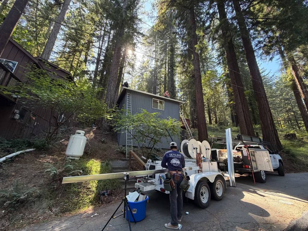Crew, truck and gutter fabrication trailer at a wooded property