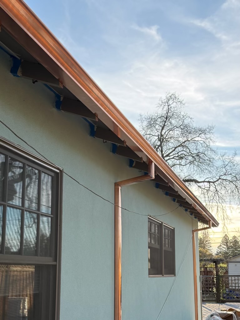 Copper seamless gutter installation stucco home golden hour