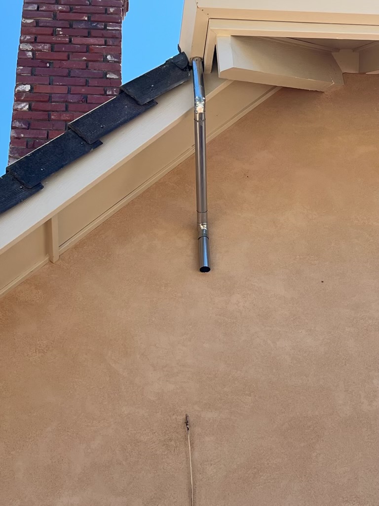 Downspout installation stucco home tile roof brick chimney